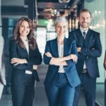 A happy team of businesspeople stand in a corporate office.