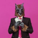 A werewolf monster holds its big dividend of cash in its paws.