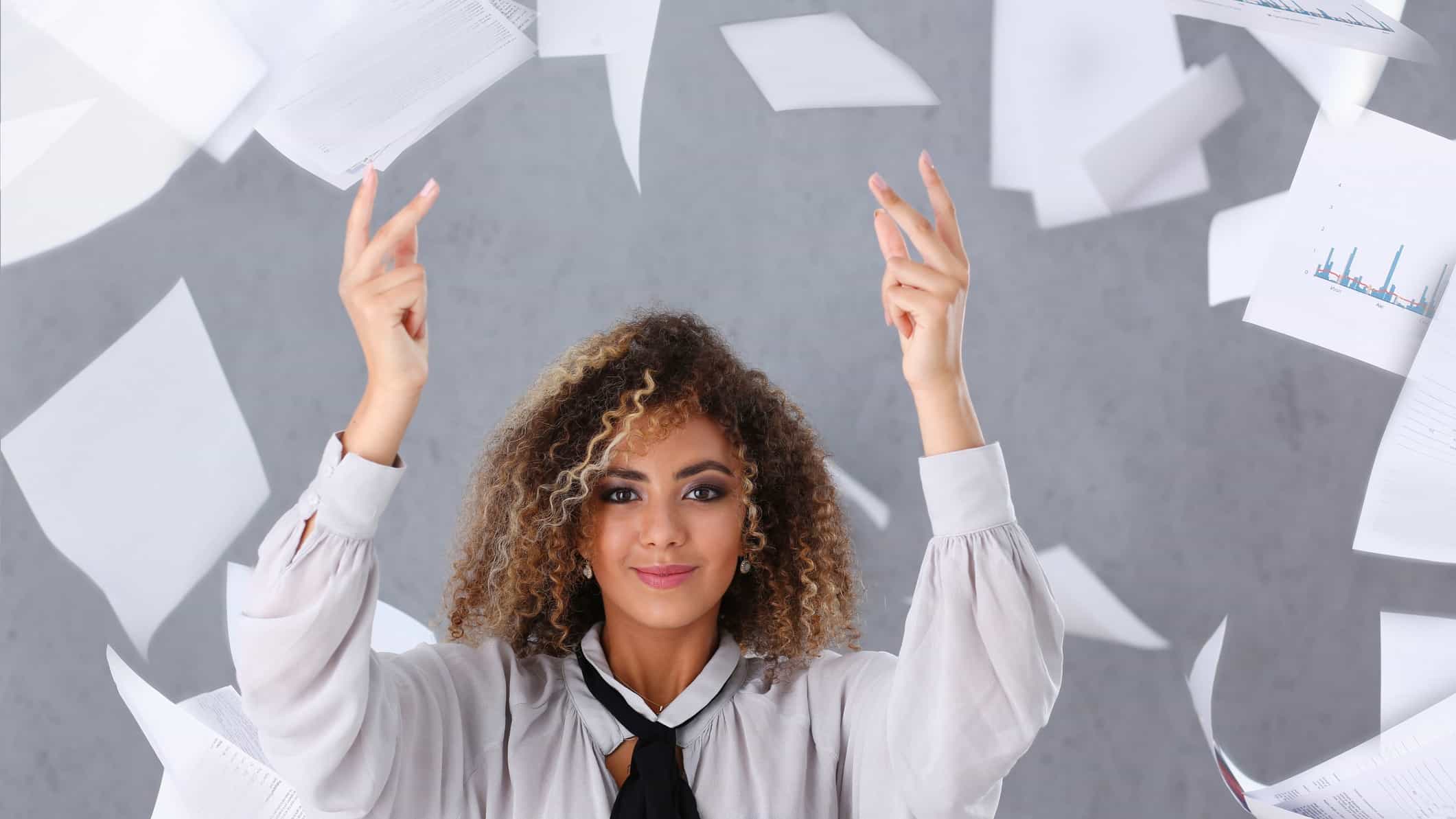 A women throws her paperwork in the air with a wry smile on her face.