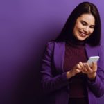 Happy woman in purple clothes looking at asx share price on mobile phone