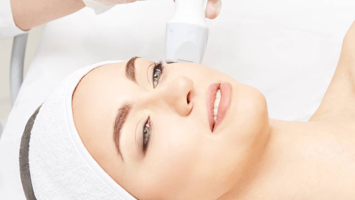 A beauty woman with bright blue eyes wearing a white headband lays on a table in a beauty clinic to receive laser therapy as the Silk Laser share price rises today