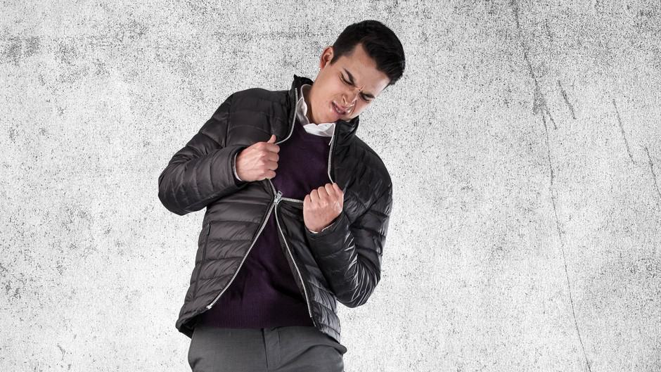 An angry man struggles with a broken zip in his jacket