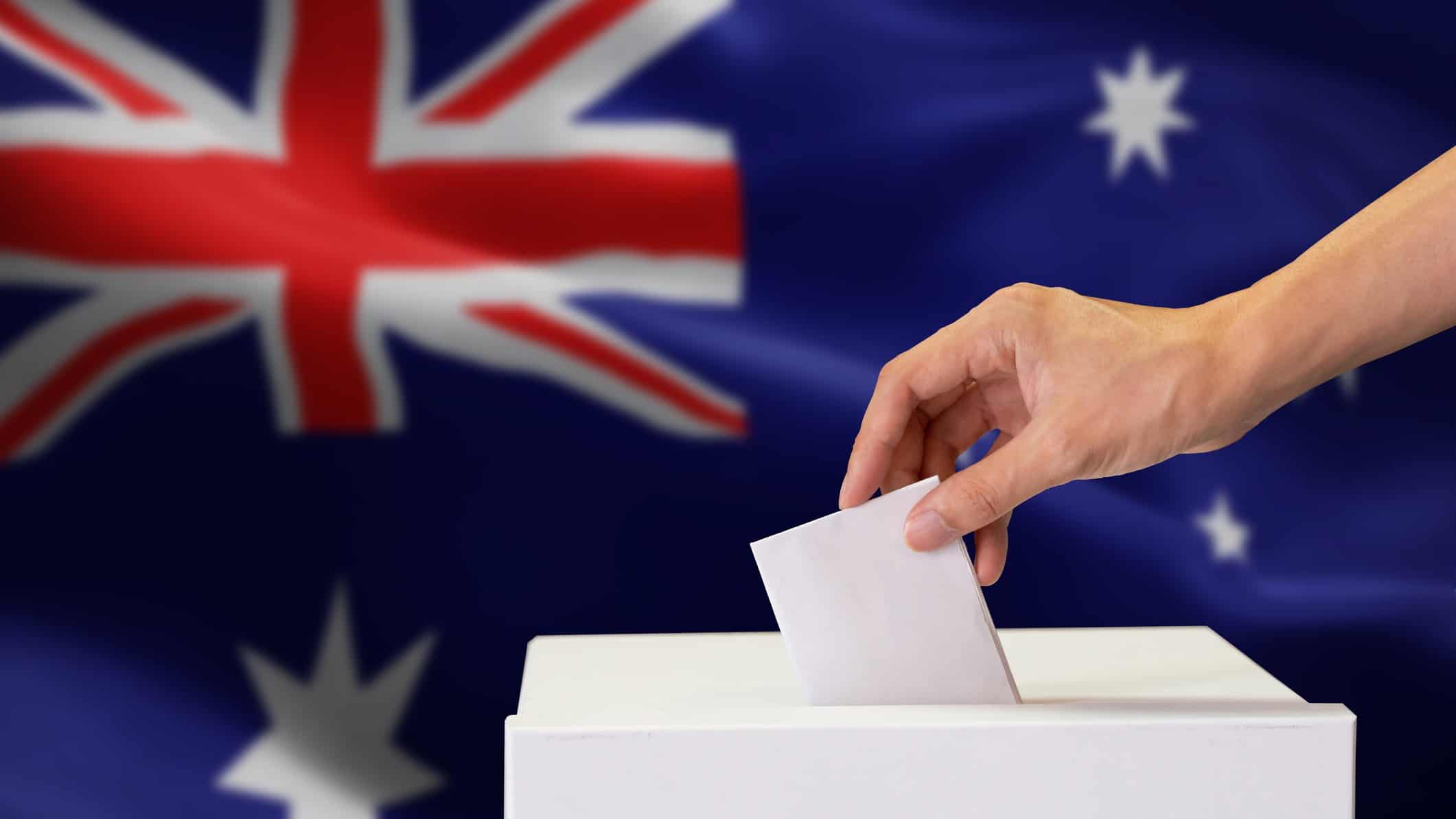 Australian flag with a ballot box and someone putting a vote in.
