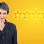 A woman has a quizzical look on her face as though she is deciding something in the foreground of a backdrop featuring five stars, like the Australian five star energy rating system.