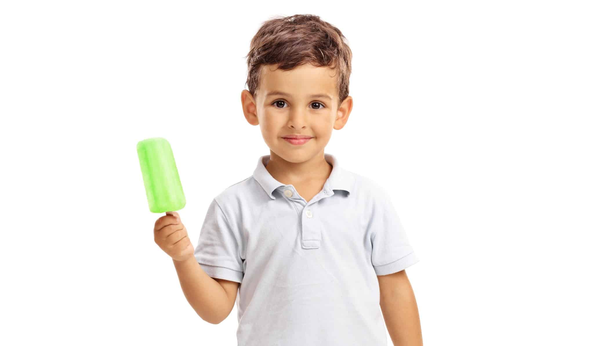 A cute little boy smiles sweetly at the camera while holding up a green ice block.