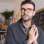 A man clasps his hands together while he looks upwards and sideways pondering how the Betashares Nasdaq 100 ETF performed in the 2022 financial year