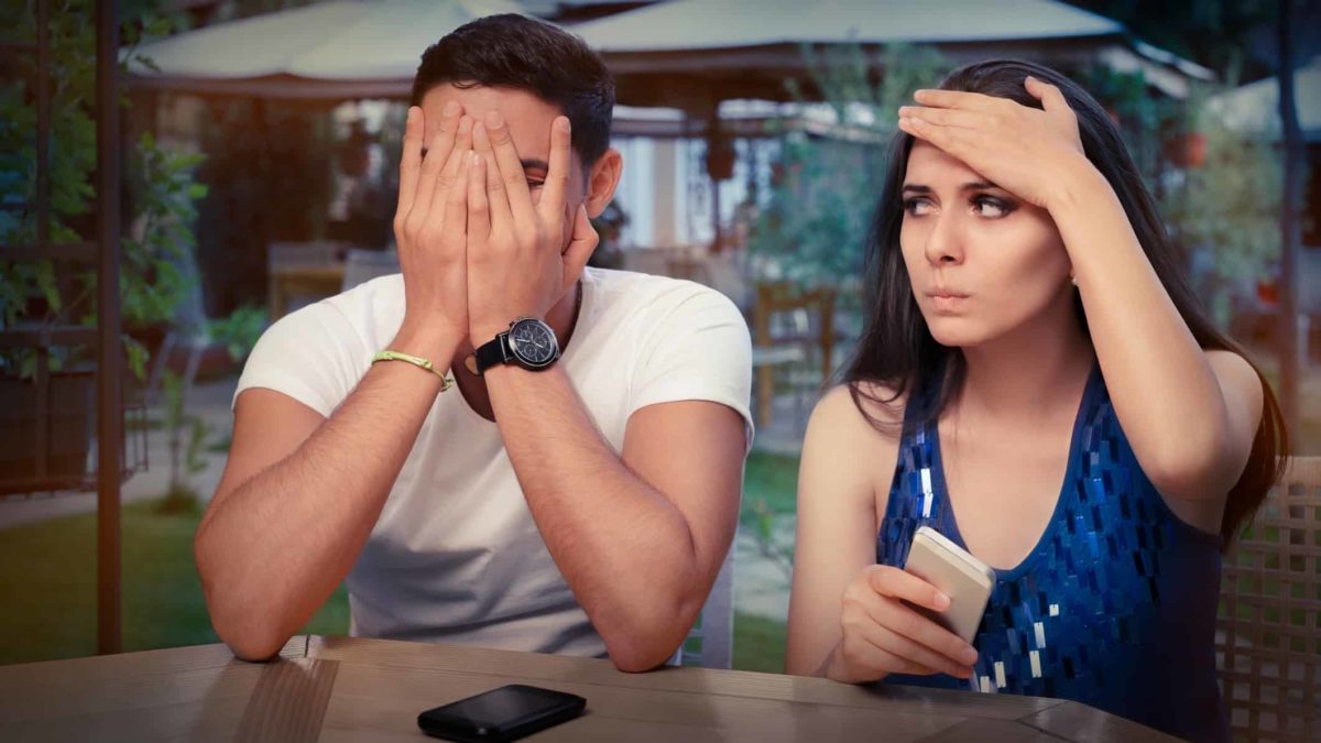 A young couple look upset as they use their phones.