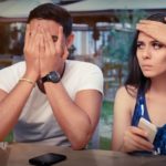 A young couple look upset as they use their phones.