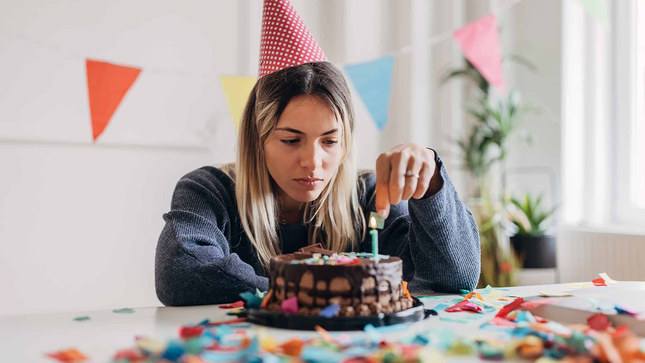 A woman stares at the candle on her cake, her birthday has fizzled.