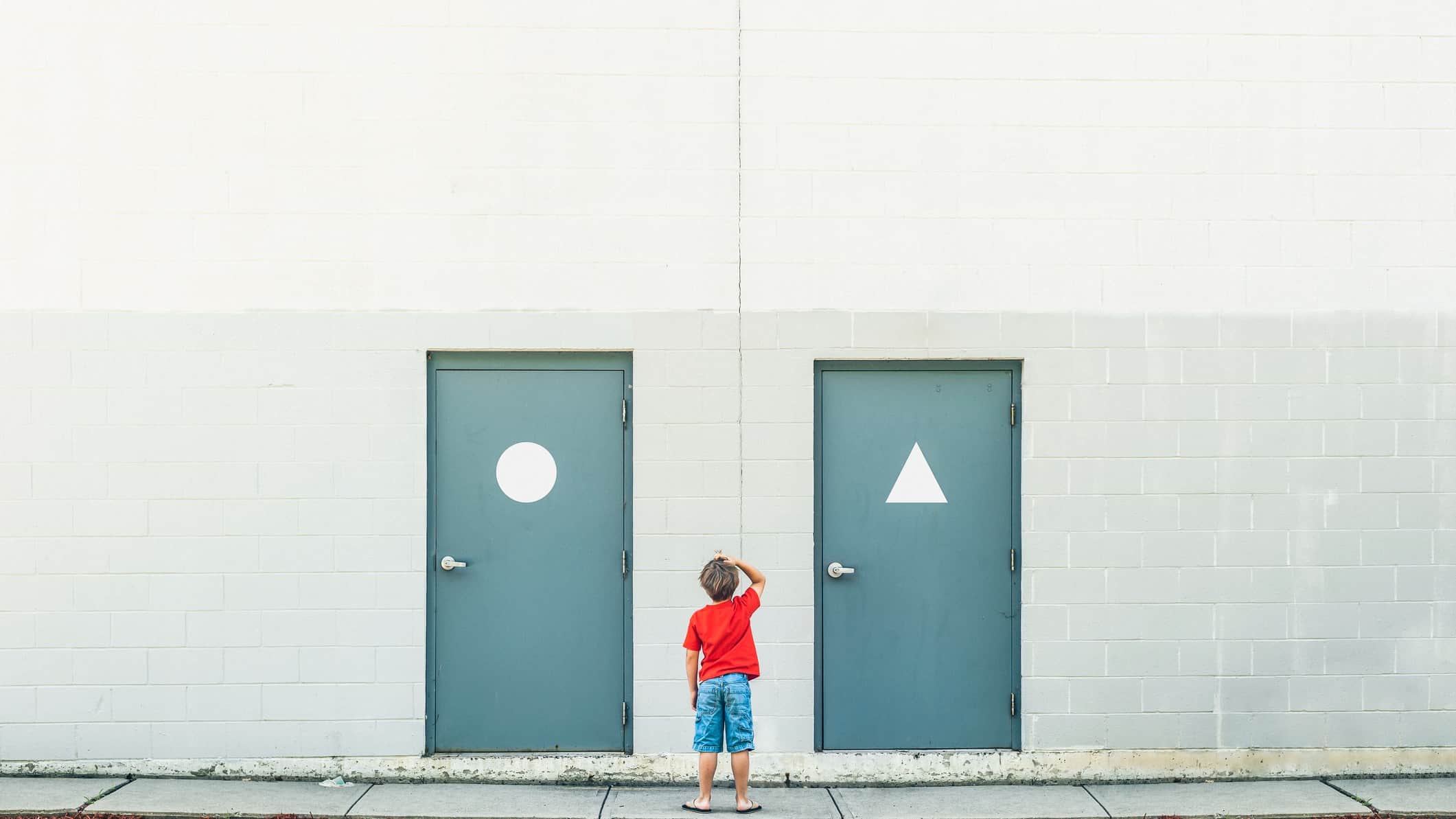 A boy stands in front of two similar but slightly different doors, scratching his head as to which one to choose.