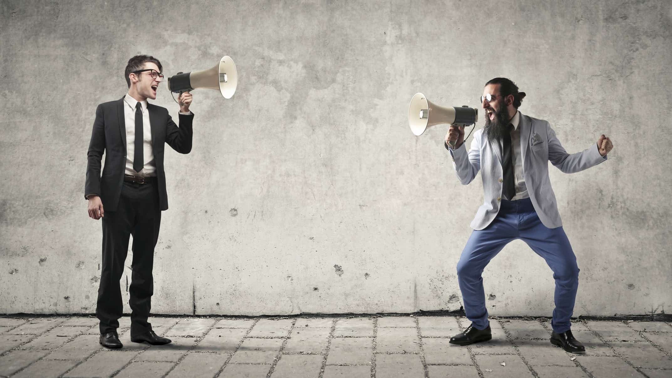 A corporate guy and an entrepreneurial guy face off, using megaphones to shout at each other.