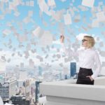 A woman stands on the roof of a city building as papers fly in the sky around her.