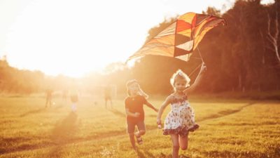 Some kids fly a kite in strong winds at sunset.