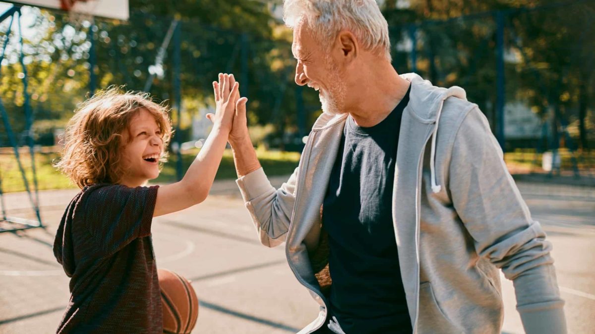 A kid and his grandad high five after a fun game of basketball.
