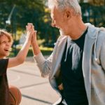 A kid and his grandad high five after a fun game of basketball.