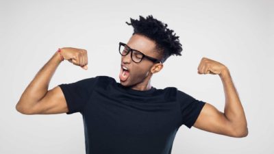 A guy wearing glasses tries to show off his muscles.