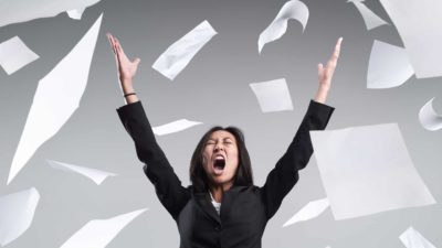 A businesswoman angrily throws her papers into the air.