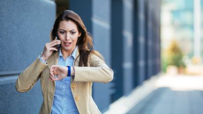 A businesswoman on the phone is shocked as she looks at her watch, she's running out of time.