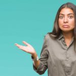 A woman shrugs and pulls awkward expression with her face.