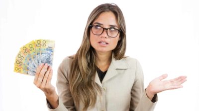 A woman looks nonplussed as she holds up a handful of Australian $50 notes.