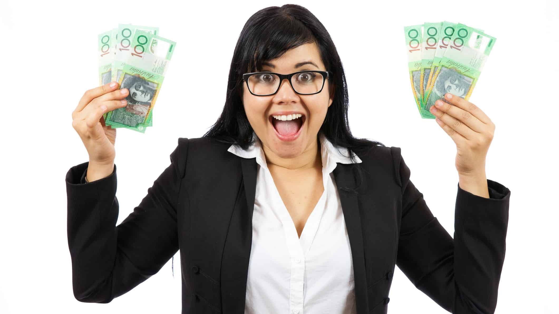A woman looks excited as she holds Australian dollars in the air.