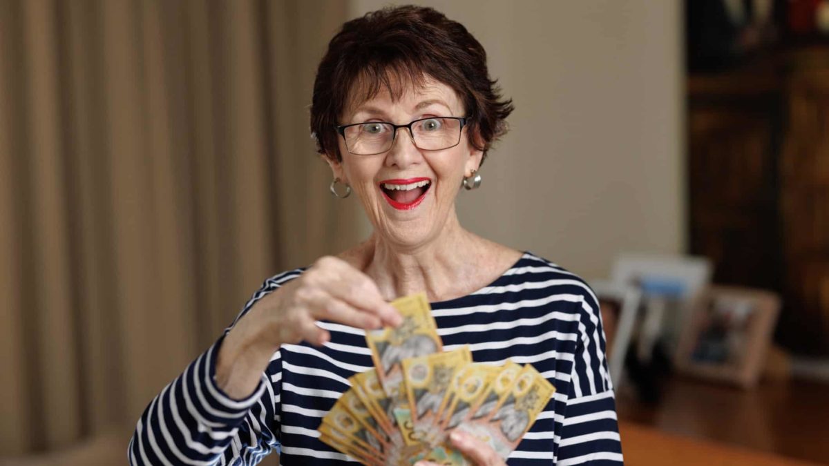 A woman holds out a handful of Australian dollars.