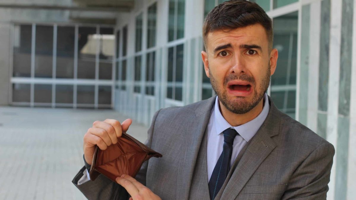 Man looks upset as he holds an empty wallet.