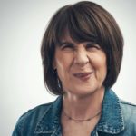 A middle-aged lady screws her face up into a wince as though imaging an uncomfortable or awkward scenario.