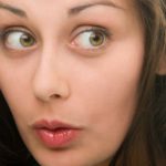 A woman gives a side eye look with her lips pursed as though she might be saying ooh at something she's hearing or learning for the first time.