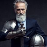 A businessman waers armour and holds a shield and sword.