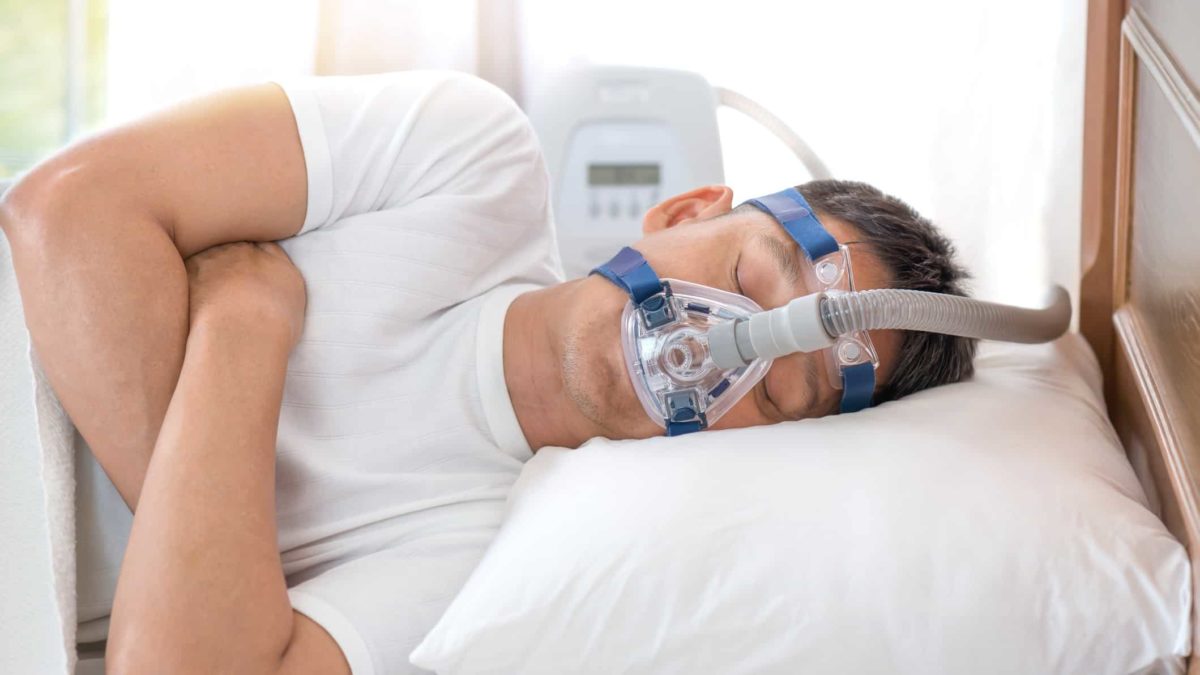 Man with a sleep apnoea mask on whilst sleeping.
