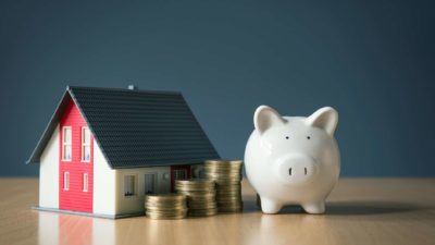 Model house with coins and a piggy bank.