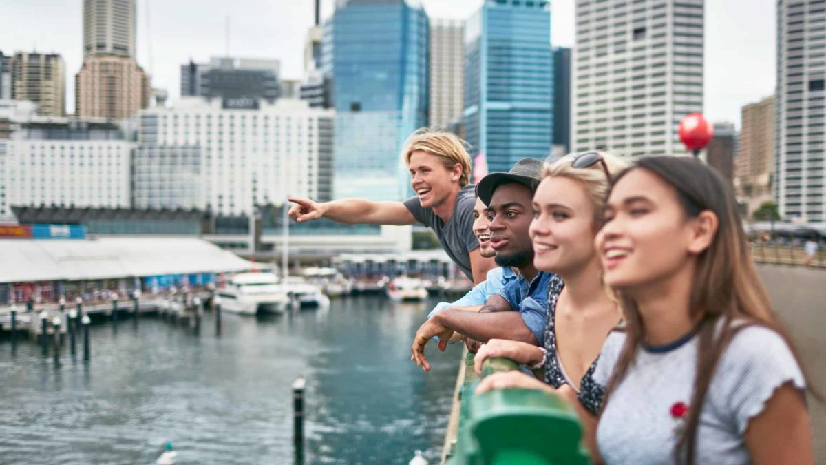 A group of young people lean over the rails overlooking Sydney's Circular Quay and check out the sights of the city around them.