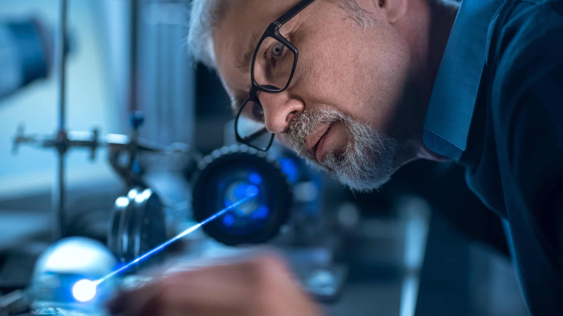 A technical manufacturer checks his work in a high-tech lab with precision equipment in the background.