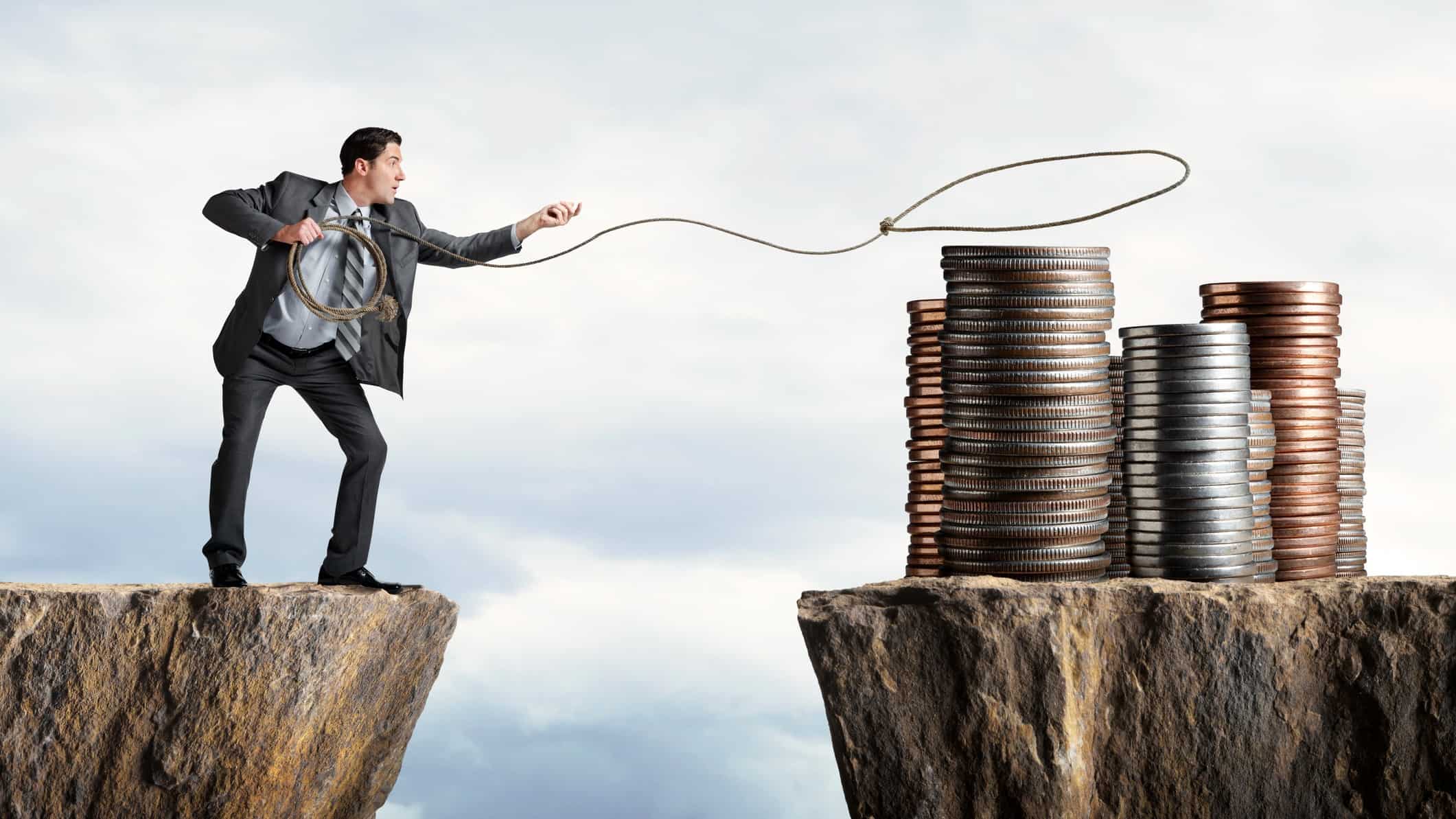 Investor trying to lasso a pile of coins across a cliff, indicatin a value trap scenario
