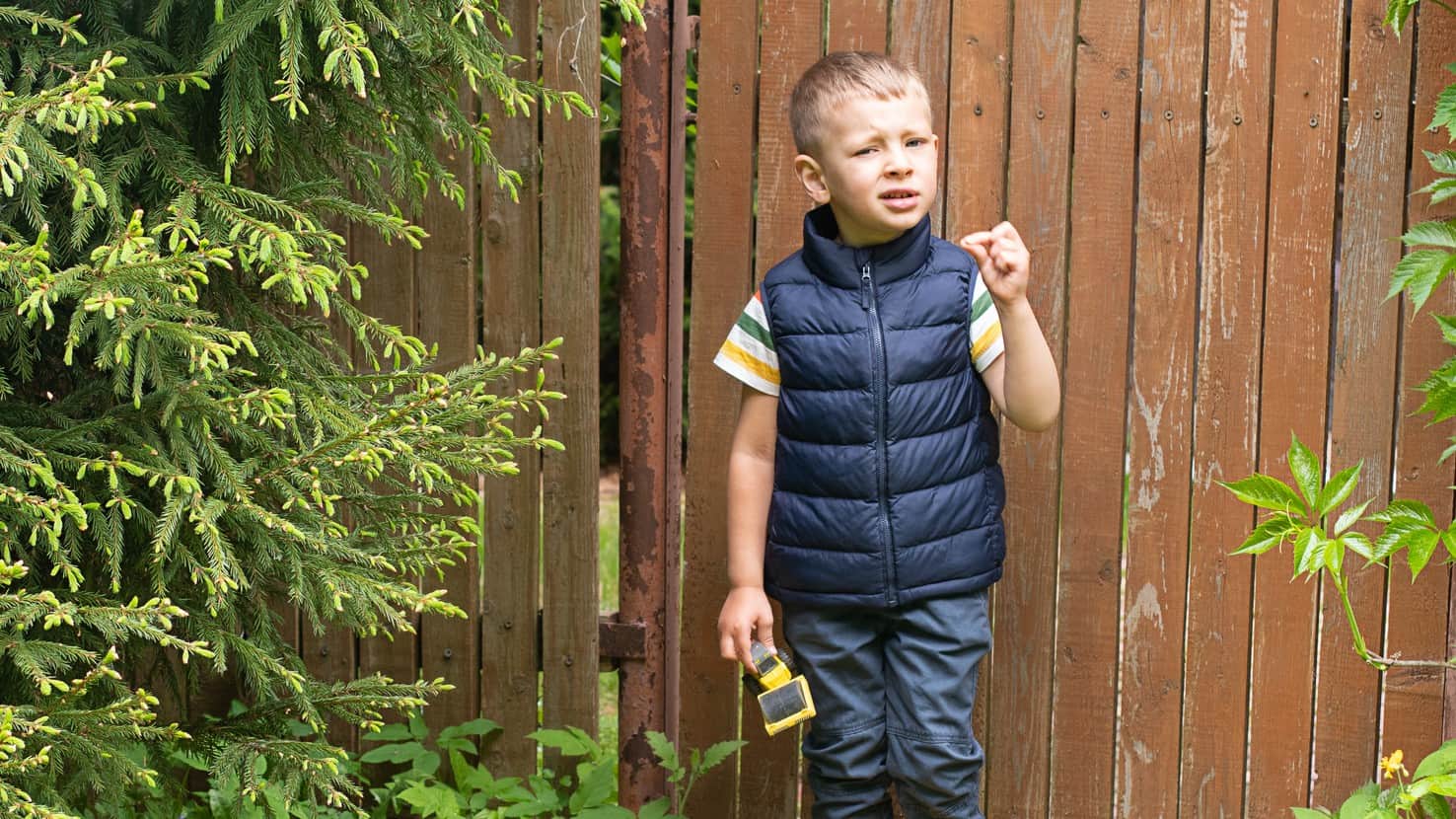 A little boy holds a toy digger with a confused look on his face.