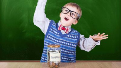 Young ASX share investor excitedly throwing hands up in front of savings jar.