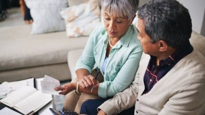 An older couple use a calculator to work out what money they have to spend.