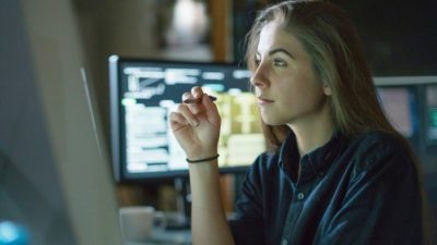 A woman sits in front of a computer and does some calculations.