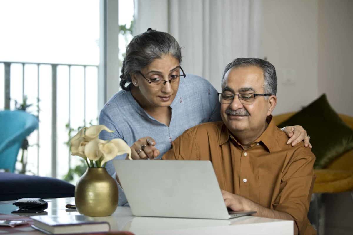 A senior couple discusses a share trade they are making on a laptop computer