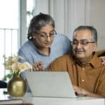 A senior couple discusses a share trade they are making on a laptop computer