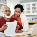 Man and woman looking over documents at computer.
