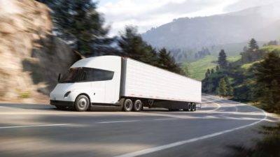 A Tesla Semi truck rounding a bend on the road.