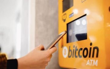 A person's hand is seen operating a Bitcoin ATM