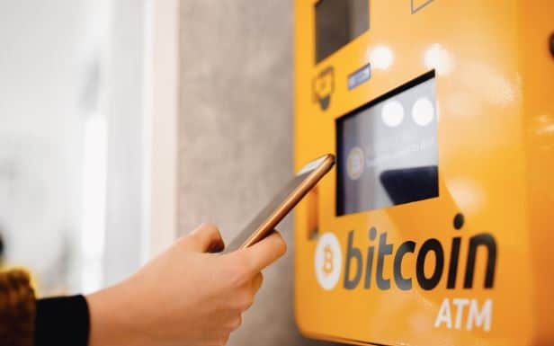 A person's hand is seen operating a Bitcoin ATM