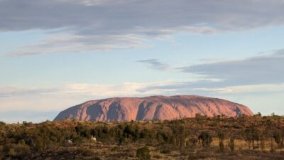 Uluru at sunrise under a majestic sky.