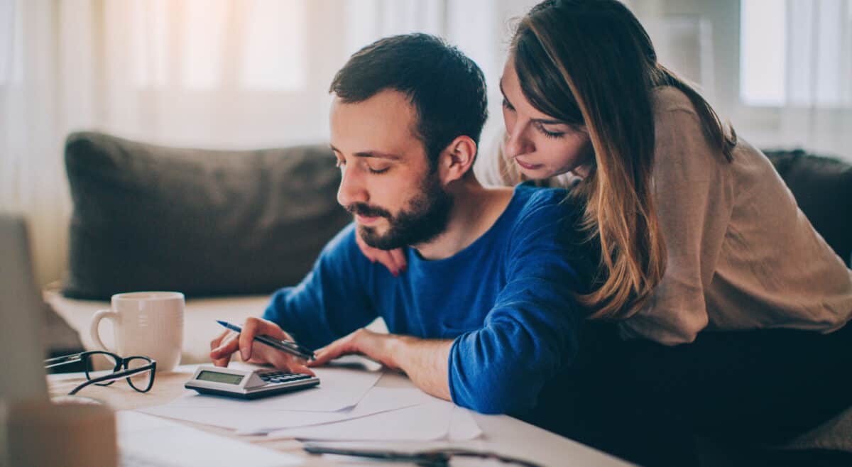 A couple sitting in their living room and checking their finances.