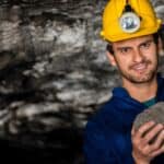 A coal miner smiling and holding a coal rock, symbolising a rising share price.