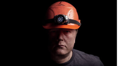 A coal miner, looking unhappy and disgruntled.