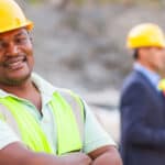 Smiling mine worker at mining site with colleagues.
